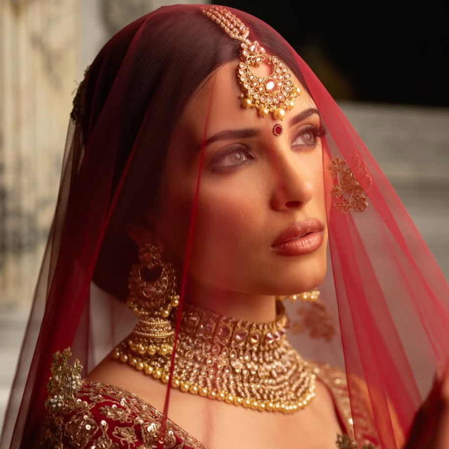 Woman wearing traditional jewelry and a red veil with a blurred background